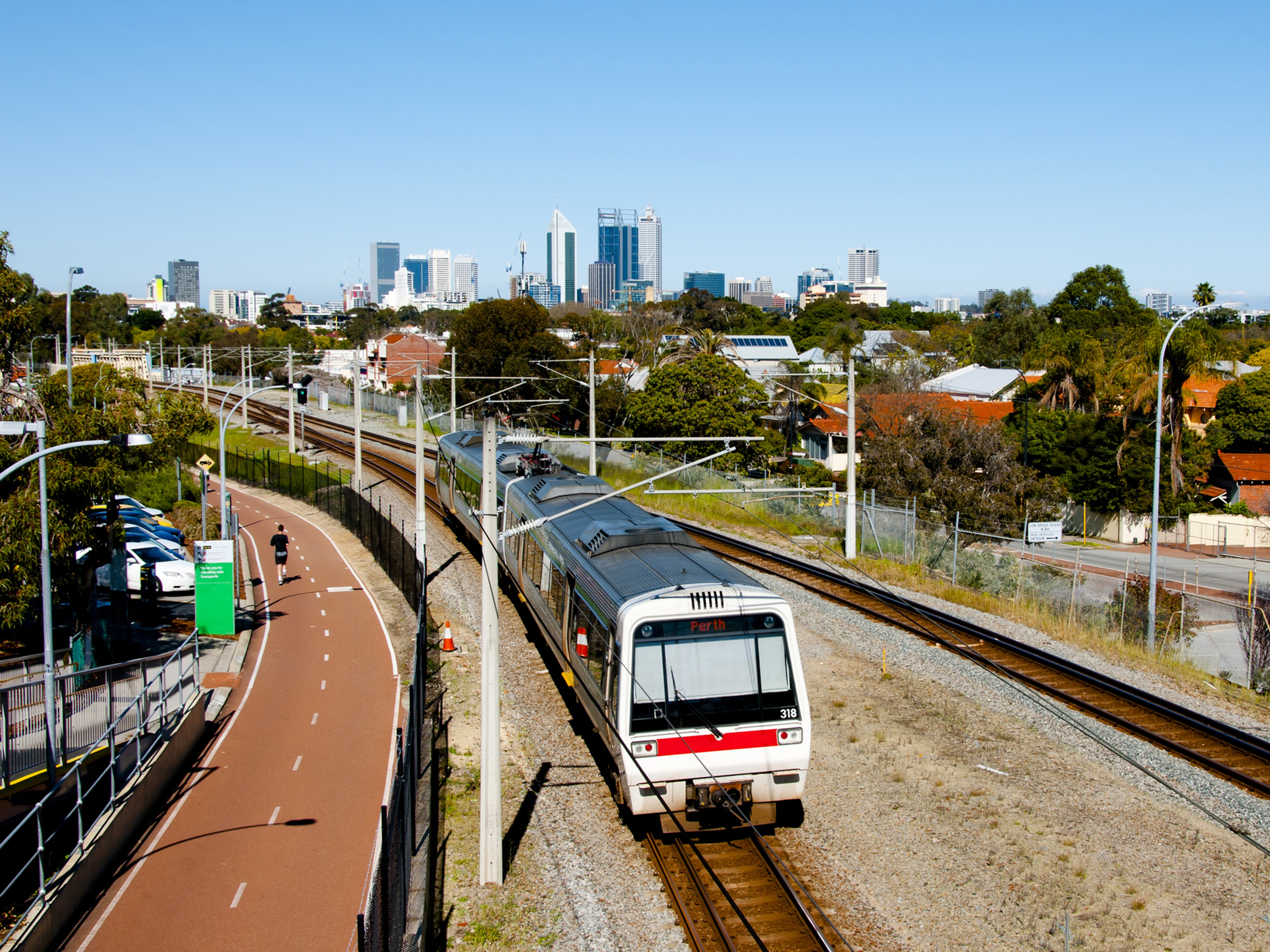 Train on train tracks, with Perth skyline in the background