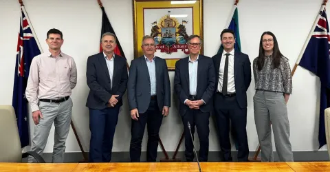 Corruption and Crime Commission standing in a row with City of Albany staff, in front of the aboriginal and Australian flags, as well as the City of Albany coat of arms